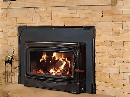 Wood-burning fireplace with a stone surround and a roaring fire.