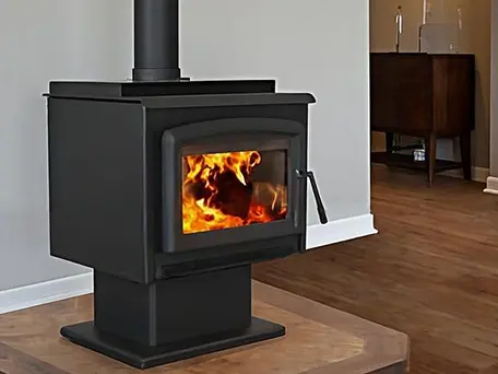 Black wood-burning stove with fire burning, sitting on a tile hearth in a modern living room.