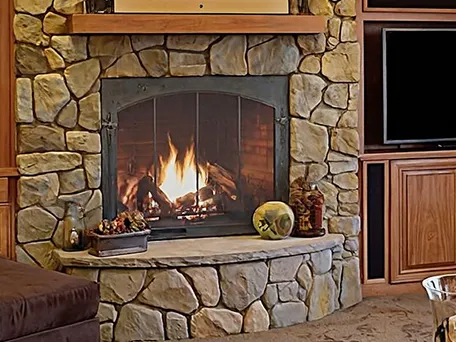 Cozy stone fireplace with a glowing fire, perfect for a relaxing evening.